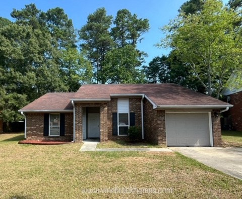 a small brick house with a lawn and trees