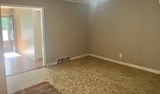 an empty living room with a rug on the floor