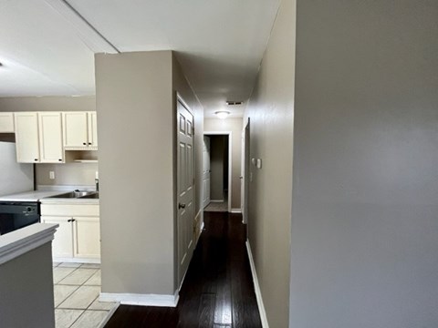 a kitchen with a long hallway with white cabinets