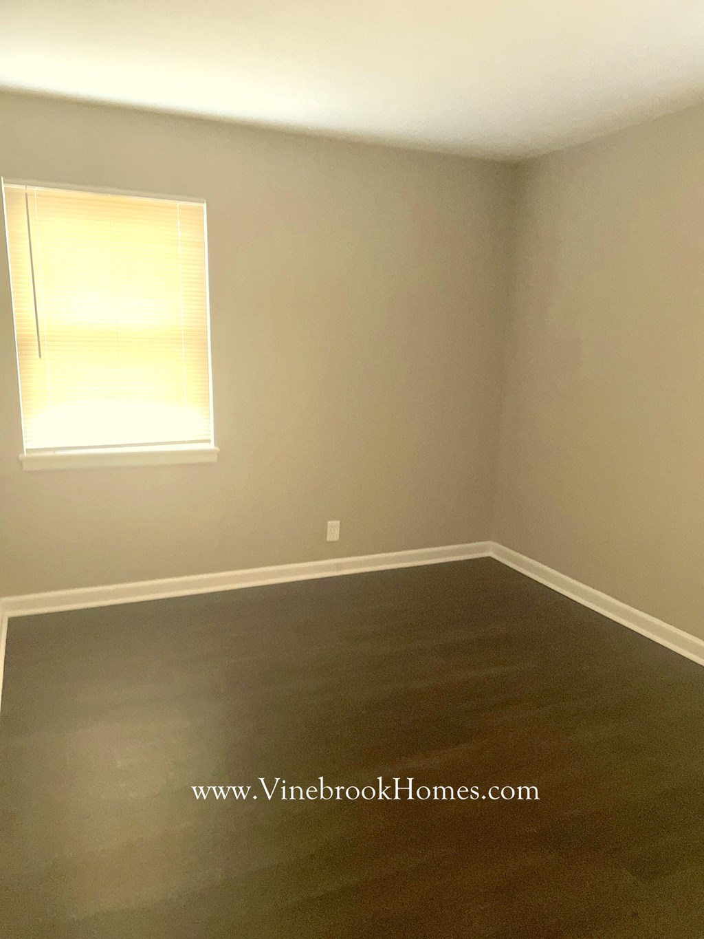 a empty room with a window and a wooden floor