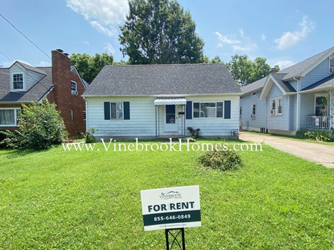 A house is for rent with a sign in front of it.