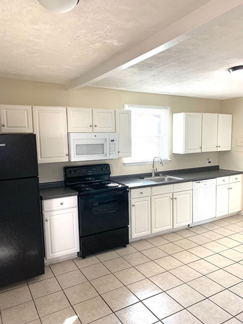 A kitchen with black appliances and white cabinets.