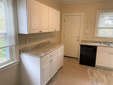 A kitchen with white cabinets and granite countertops is shown.