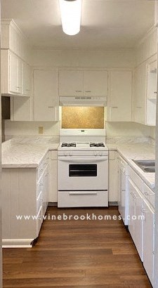 a kitchen with white cabinets and a white stove