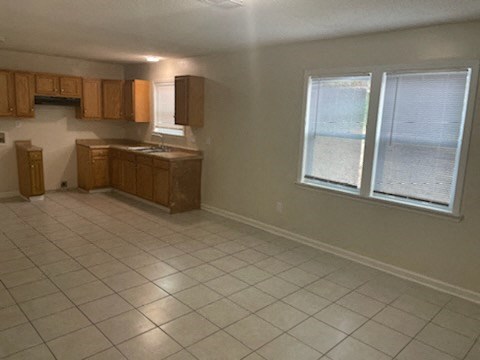 an empty kitchen with a tiled floor and a window