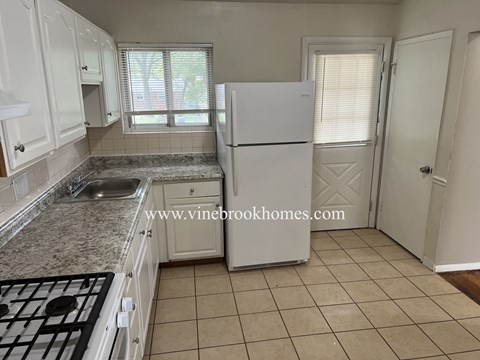 A kitchen with a white fridge and a black stove top.
