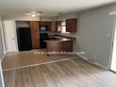A kitchen with a black fridge and wooden cabinets.