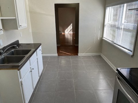 A kitchen with white cabinets and a black counter top.