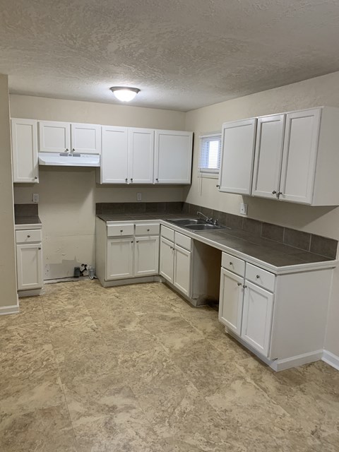 A kitchen with white cabinets and a countertop.