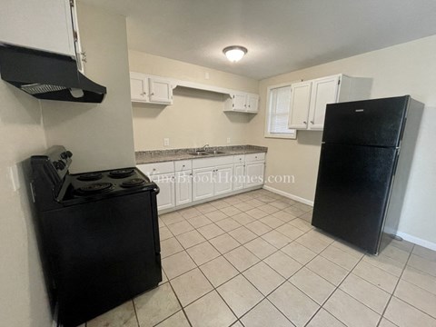 a kitchen with white cabinets and black appliances and a black refrigerator