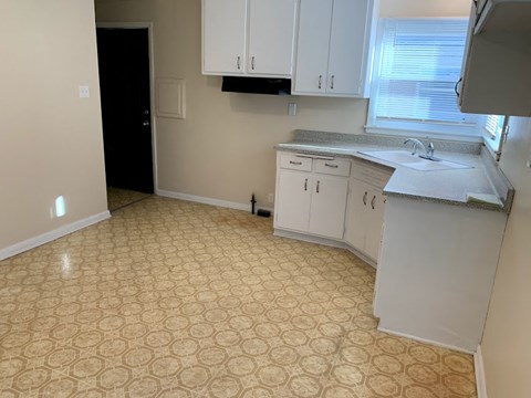 A kitchen with white cabinets and a patterned floor.