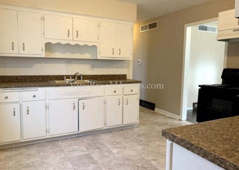 A kitchen with white cabinets and a granite countertop.