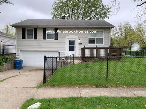 the front of a house with a yard and a fence