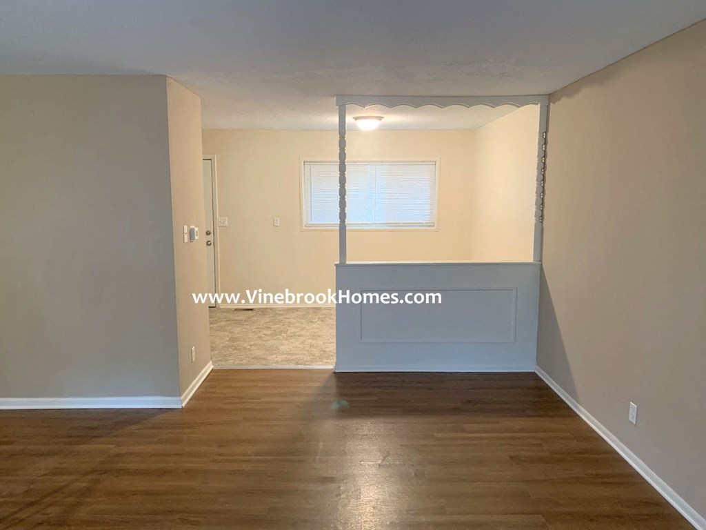 an empty living room with wood floors and a window