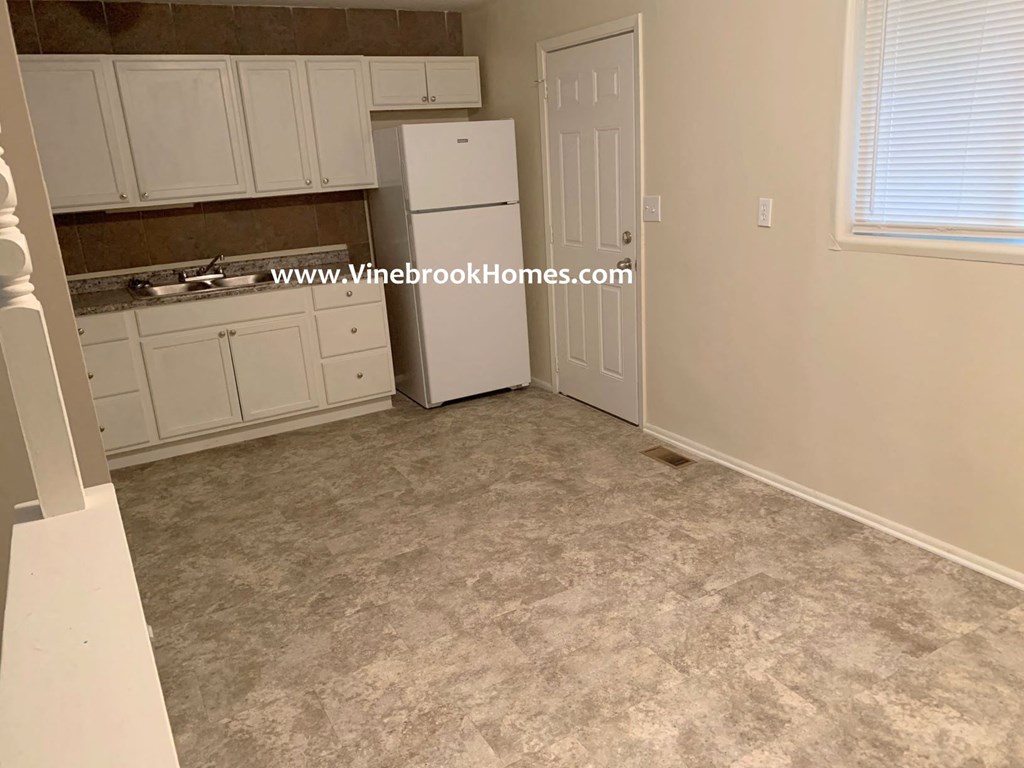 a kitchen with white cabinets and a white refrigerator