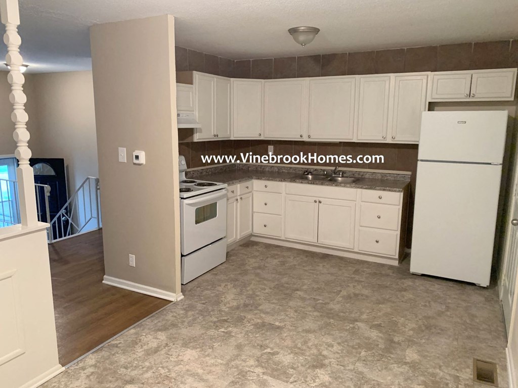 an empty kitchen with white appliances and white cabinets