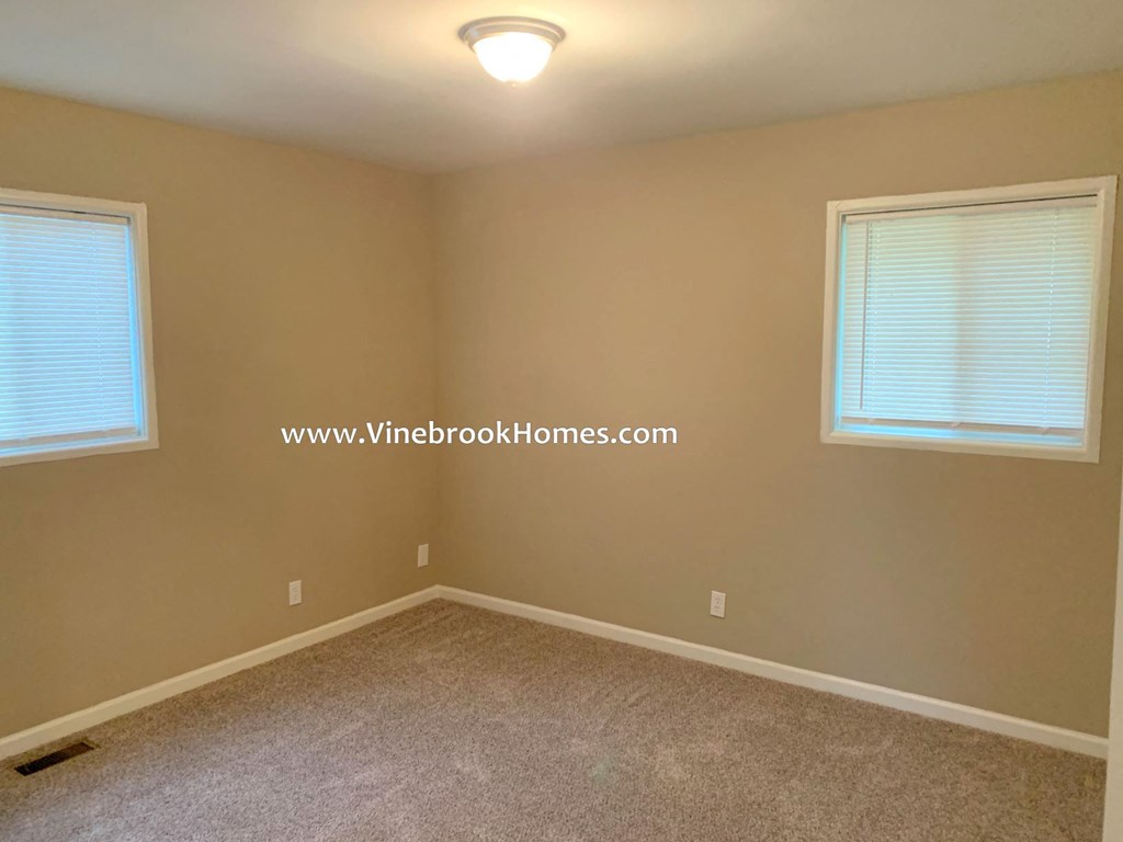 a bedroom with a carpeted floor and two windows