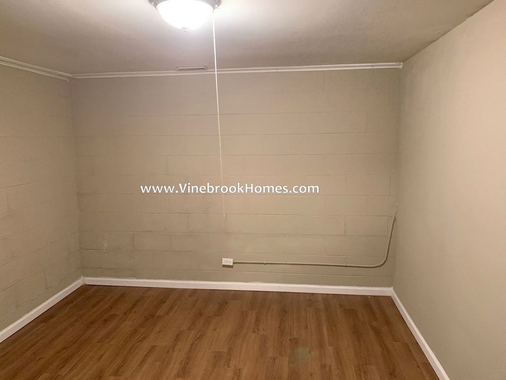 a small room with a wood floor and white tiled walls
