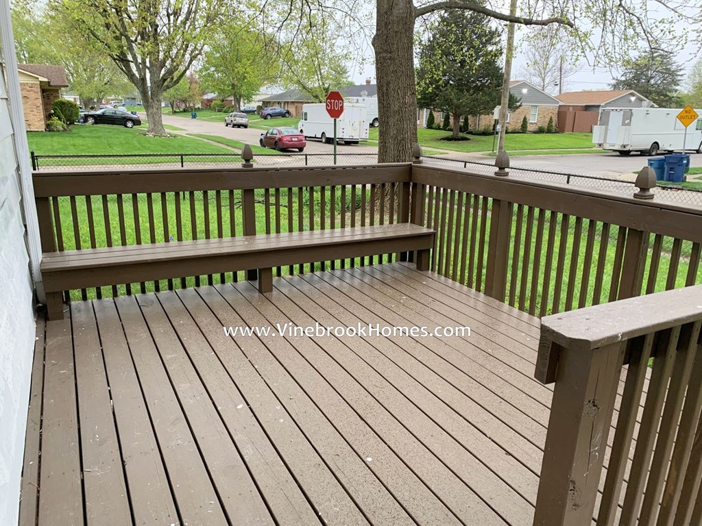 the deck of a home has a bench and a stop sign