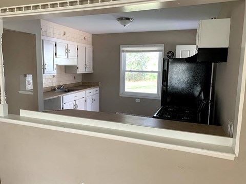A kitchen with white cabinets and a black fridge.