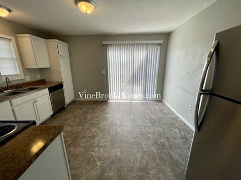A kitchen with a refrigerator, sink, and cabinets.