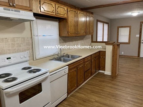 A kitchen with a white stove and wooden cabinets.