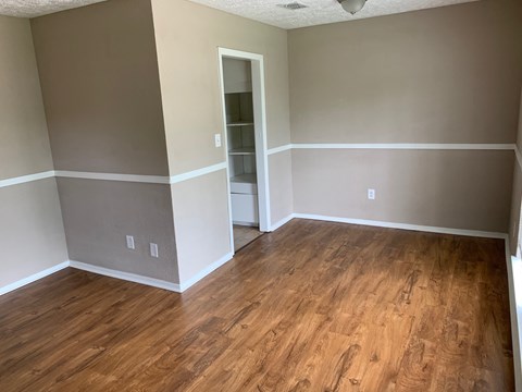 a living room with wooden floors and grey walls and a closet