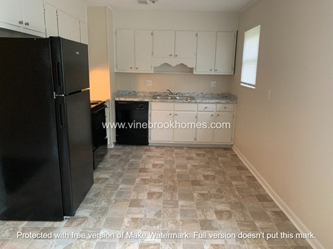 a kitchen with white cabinets and a black refrigerator