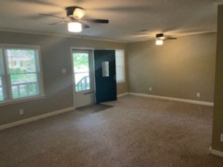an empty living room with a ceiling fan and a door