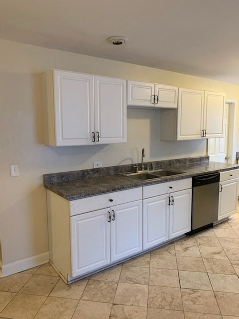 A kitchen with white cabinets and a granite countertop.