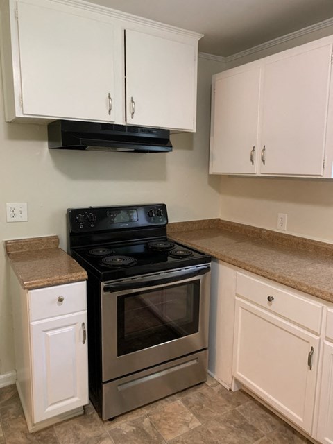 A kitchen with a black stove top oven and white cabinets.