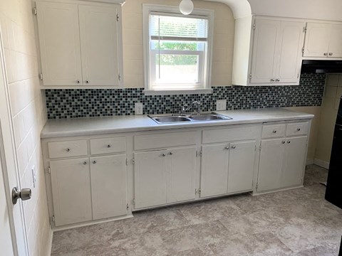 A kitchen with white cabinets and a window above the sink.