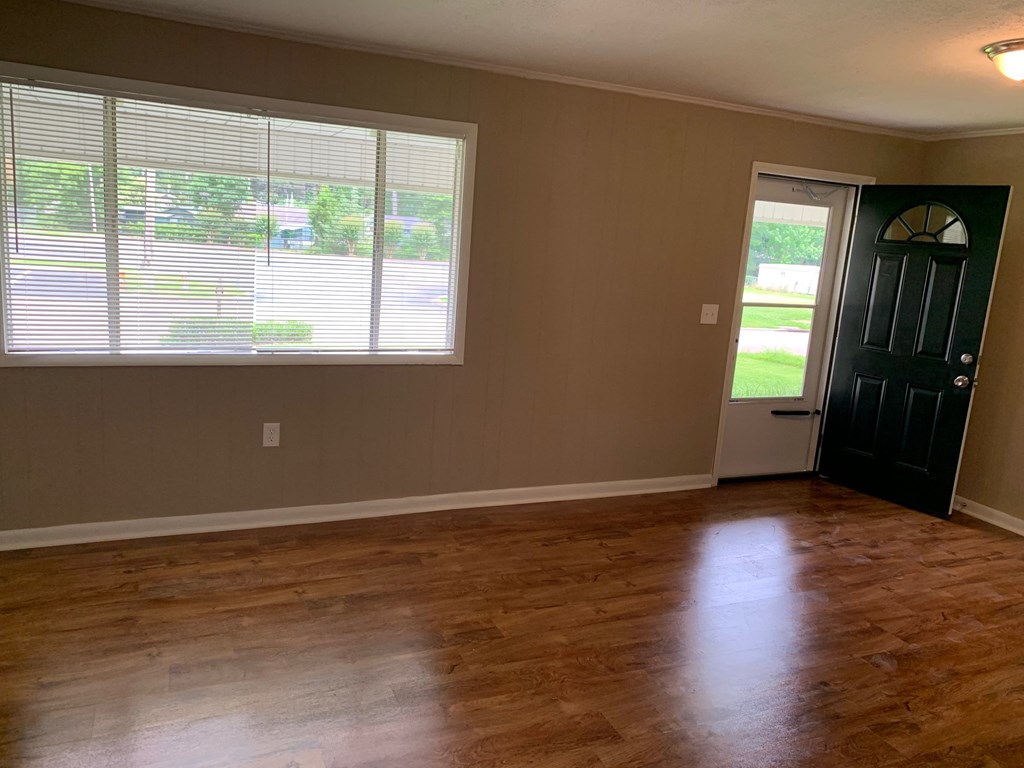 A room with a black door and a window with blinds.