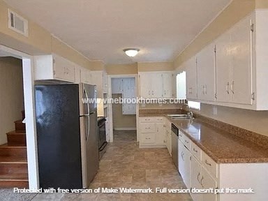 A kitchen with white cabinets and a black refrigerator.