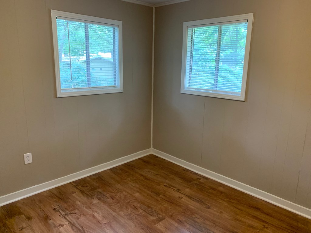 A room with two windows and wooden flooring.