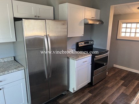 A kitchen with a stainless steel refrigerator and white cabinets.
