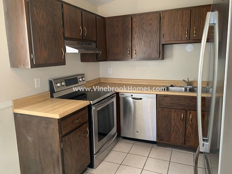 A kitchen with wooden cabinets and a stainless steel dishwasher.