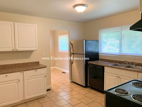 A kitchen with white cabinets and a black stove top oven.