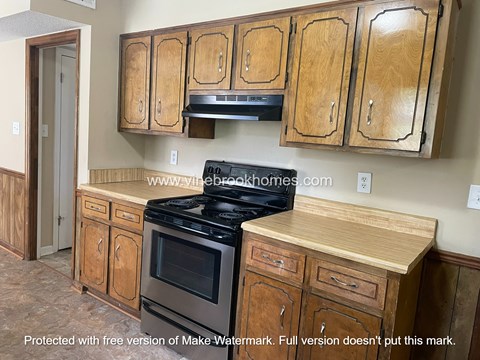 A kitchen with wooden cabinets and a stove top oven.