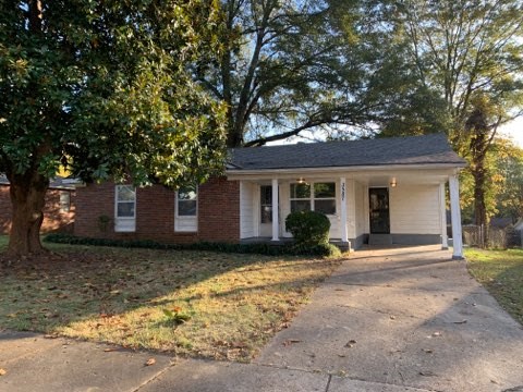 a small brick house with a tree in front of it