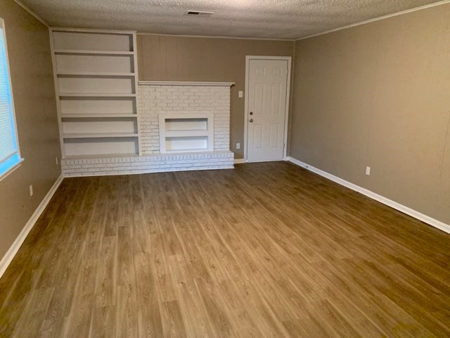 an empty living room with wood floors and a fireplace