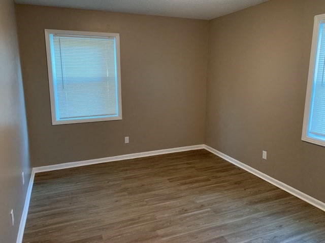 a empty room with a wooden floor and two windows