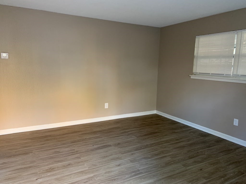 an empty living room with wood floors and a window