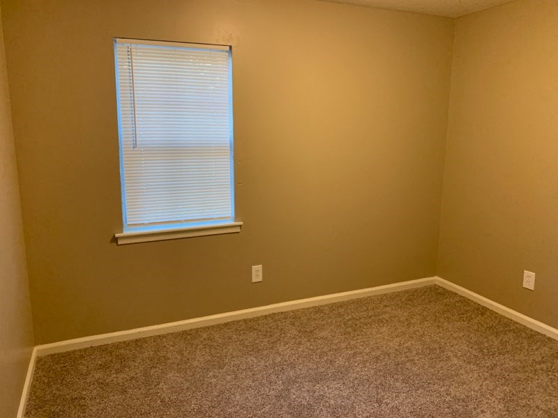 a empty room with a window and a carpet