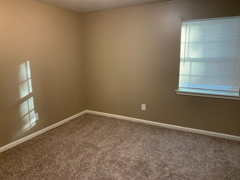 a empty room with a window and a carpet