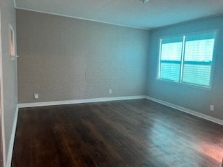 an empty bedroom with wood floors and a window