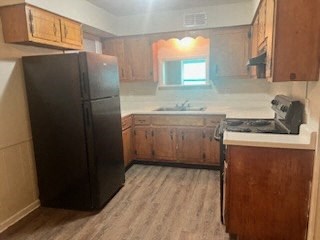 a kitchen with a black refrigerator and a sink