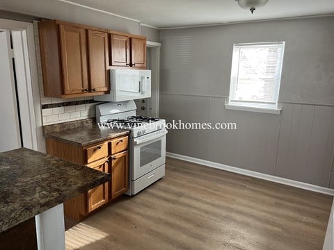 a small kitchen with a stove and a microwave and wooden cabinets