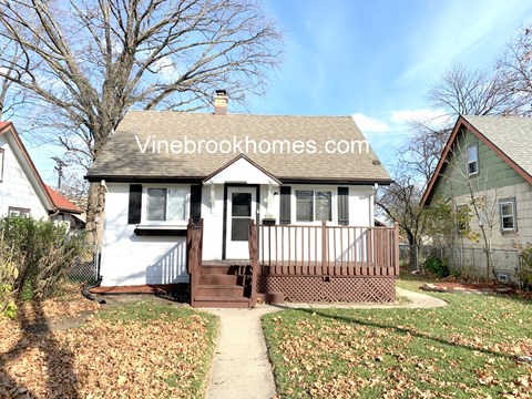 a small white house with a porch and a sidewalk