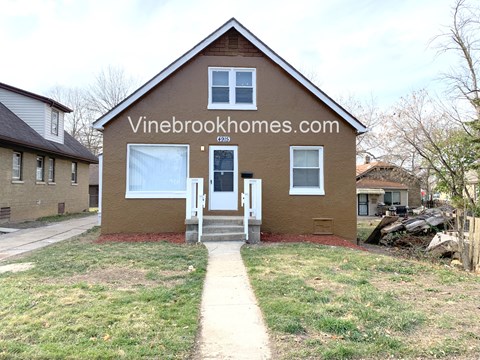the front of a brown house with a sidewalk in front